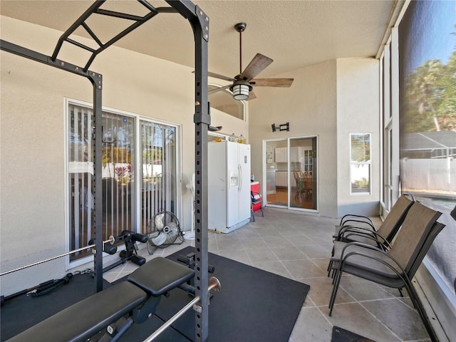 workout room with ceiling fan and a textured ceiling