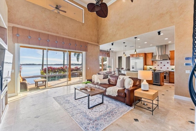 living room featuring a water view, ceiling fan, and a high ceiling