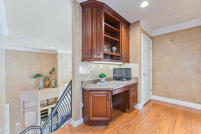 kitchen featuring crown molding, built in desk, and light wood-type flooring