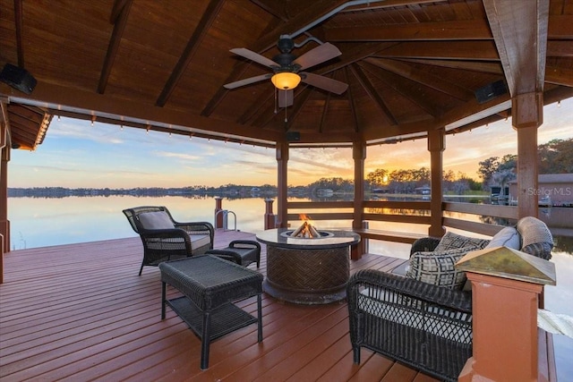 dock area featuring a deck with water view, a gazebo, and an outdoor fire pit