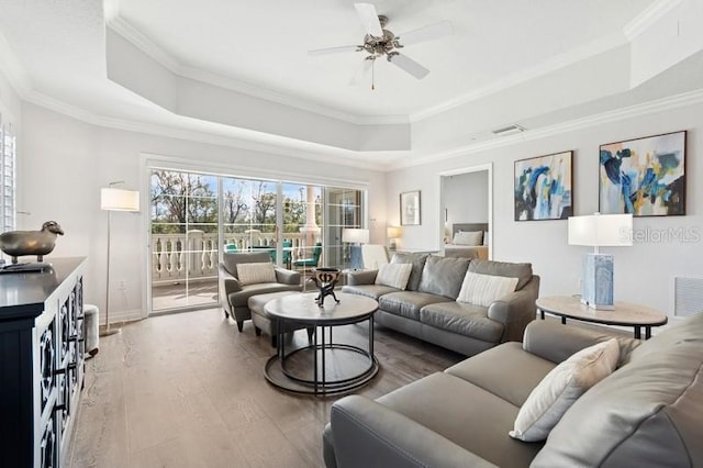 living room featuring crown molding, hardwood / wood-style floors, ceiling fan, and a tray ceiling