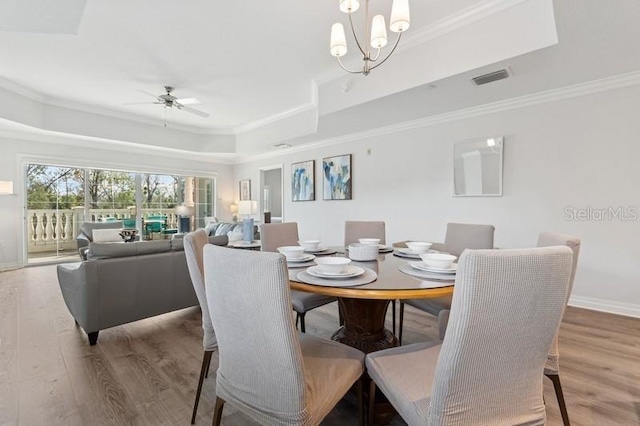 dining area featuring a raised ceiling, wood-type flooring, and ornamental molding