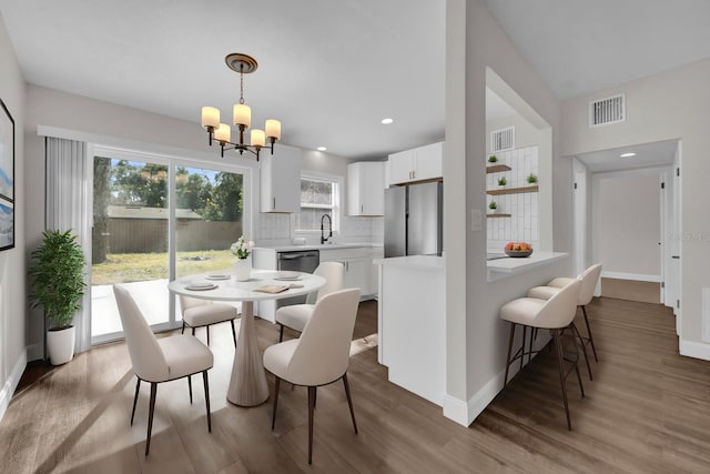 dining room with sink, a notable chandelier, and wood-type flooring