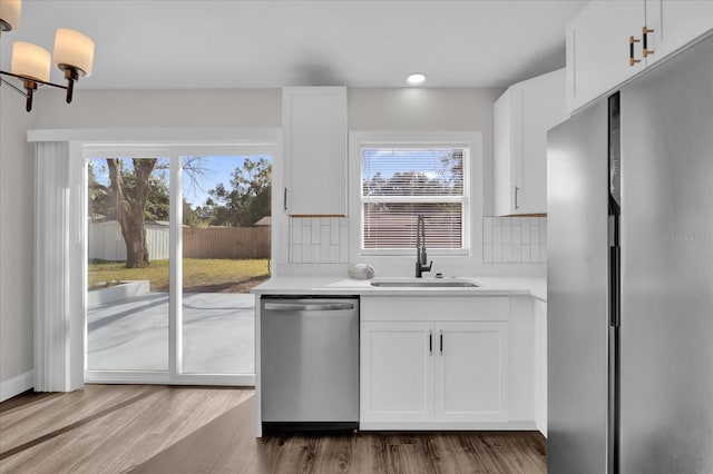 kitchen with sink, wood-type flooring, white cabinets, and appliances with stainless steel finishes