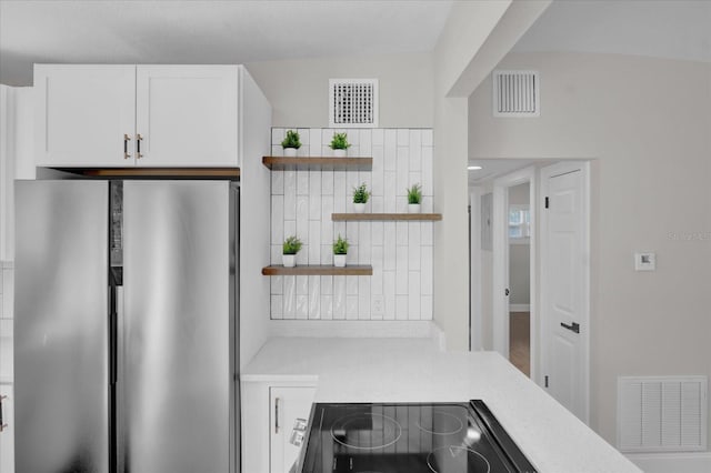 kitchen featuring stainless steel refrigerator, stove, backsplash, and white cabinets