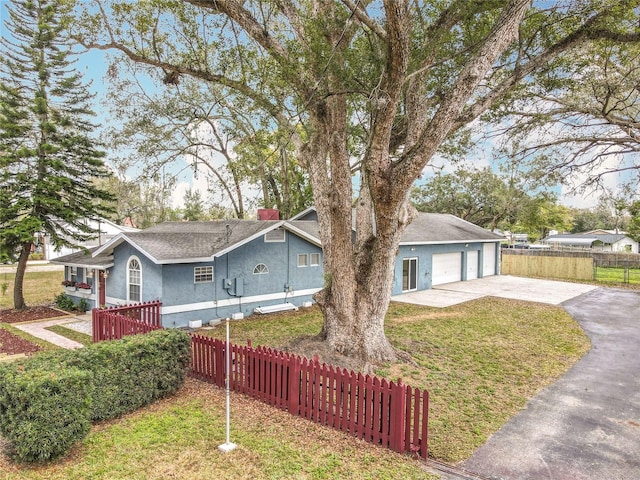 view of front of property with a front lawn, a detached garage, fence, and stucco siding