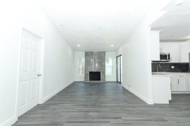 unfurnished living room with sink, a high end fireplace, and light hardwood / wood-style floors