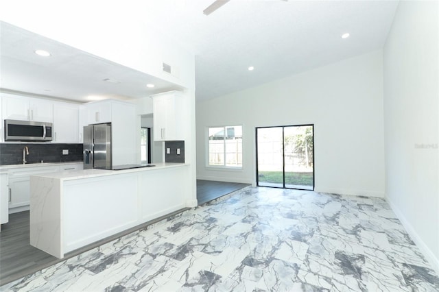 kitchen with sink, white cabinetry, tasteful backsplash, kitchen peninsula, and stainless steel appliances