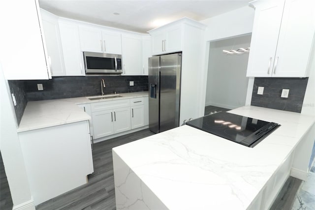 kitchen with appliances with stainless steel finishes, kitchen peninsula, sink, and white cabinets