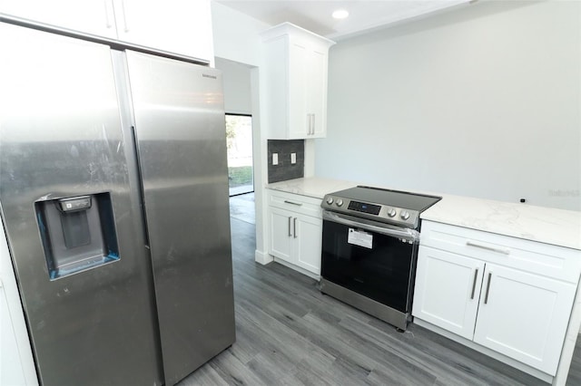 kitchen with dark wood-type flooring, light stone counters, white cabinets, stainless steel appliances, and backsplash