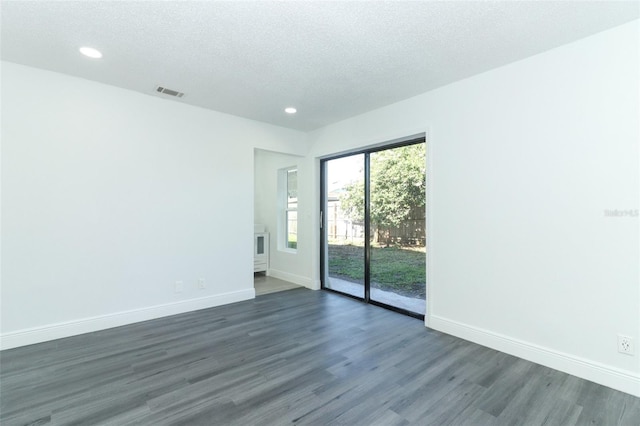 empty room with dark hardwood / wood-style floors and a textured ceiling