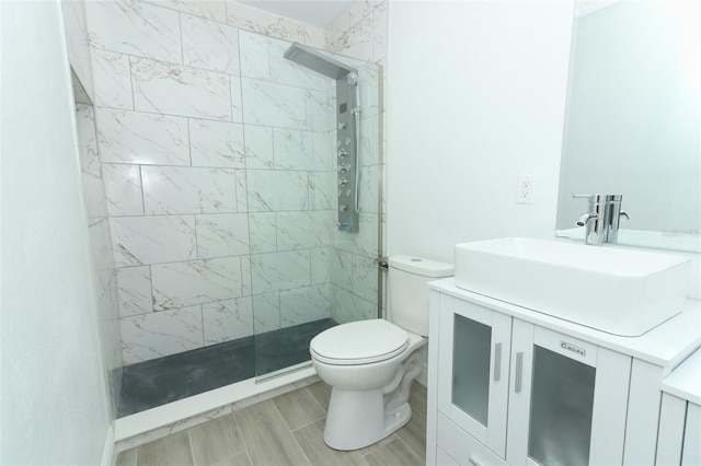 bathroom with vanity, a tile shower, and toilet