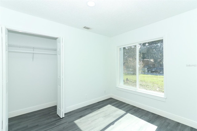 unfurnished bedroom with dark wood-type flooring, a closet, and a textured ceiling