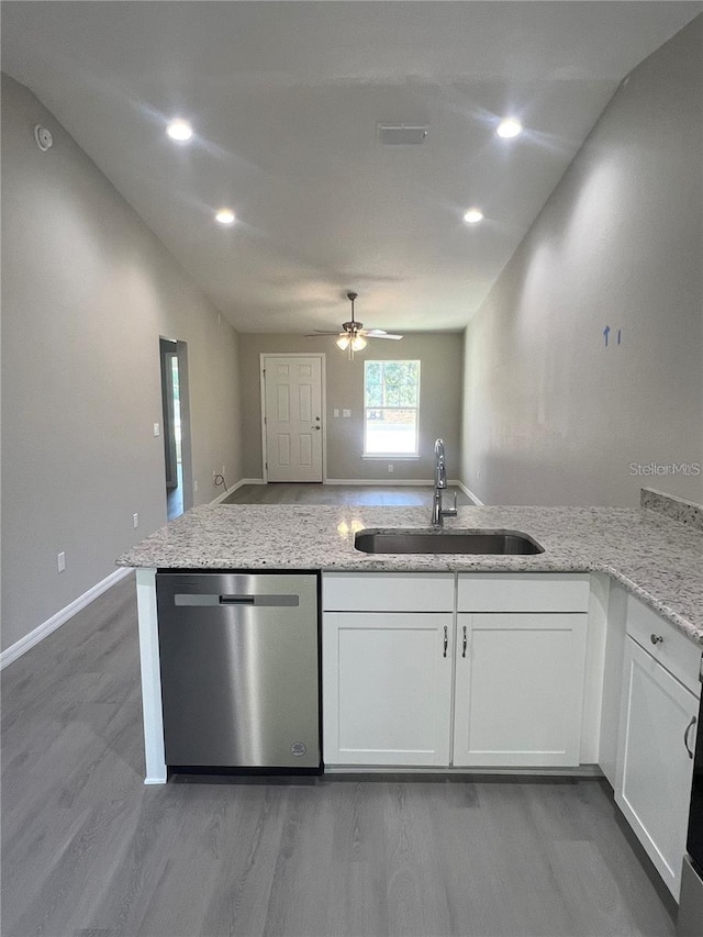 kitchen with sink, white cabinetry, light stone counters, stainless steel dishwasher, and kitchen peninsula