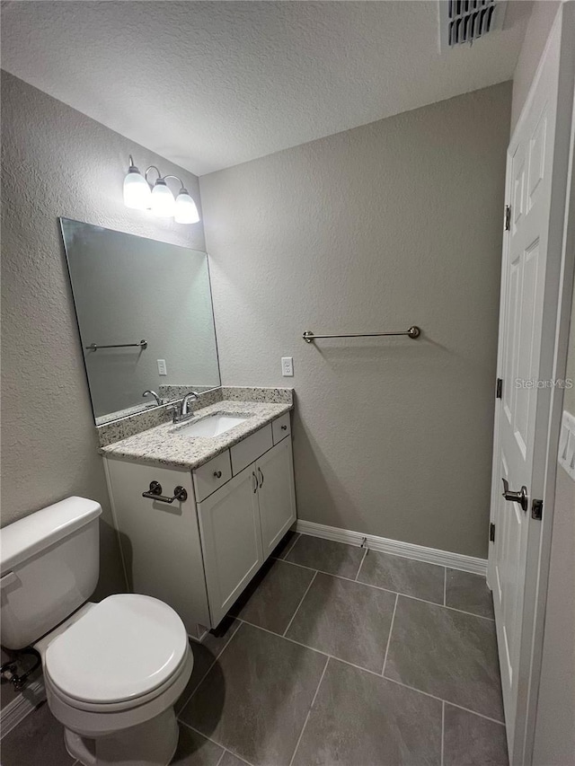 bathroom with vanity, tile patterned floors, a textured ceiling, and toilet