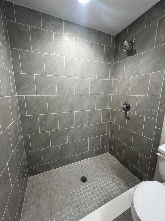 bathroom with a tile shower and toilet