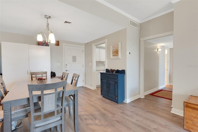 dining space featuring ornamental molding, light hardwood / wood-style floors, and a notable chandelier