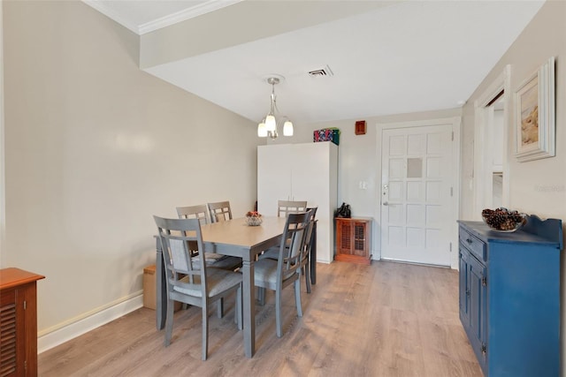 dining space with ornamental molding and light hardwood / wood-style floors