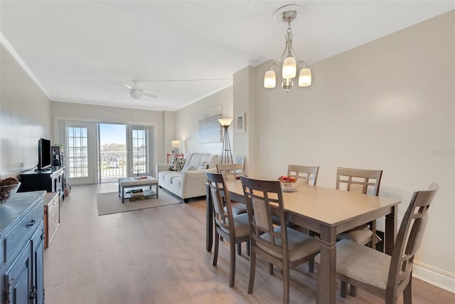 dining room with hardwood / wood-style flooring, crown molding, and ceiling fan with notable chandelier