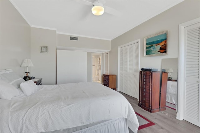 bedroom with crown molding, ensuite bath, multiple closets, ceiling fan, and light hardwood / wood-style floors