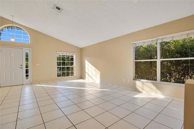 foyer with light tile patterned floors, vaulted ceiling, a textured ceiling, and plenty of natural light