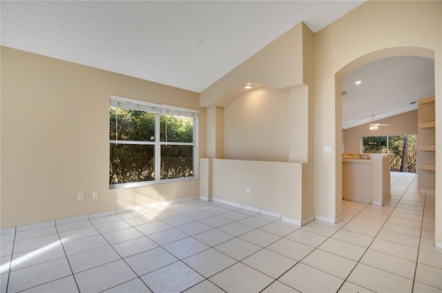 empty room featuring ceiling fan, lofted ceiling, and light tile patterned floors