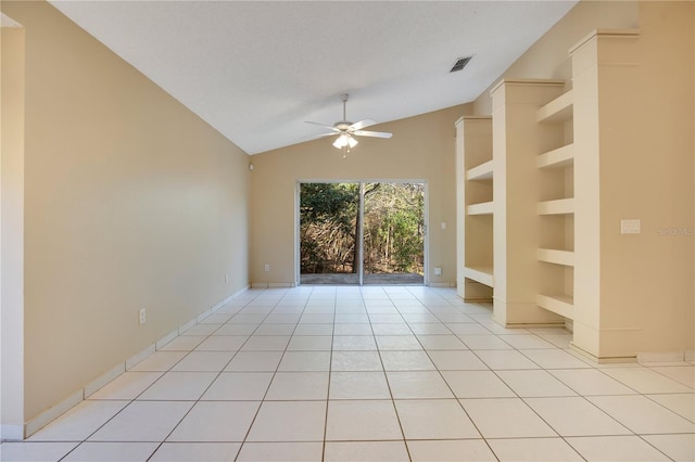 tiled empty room with ceiling fan, vaulted ceiling, a textured ceiling, and built in shelves