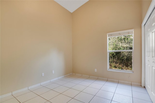 tiled spare room with vaulted ceiling