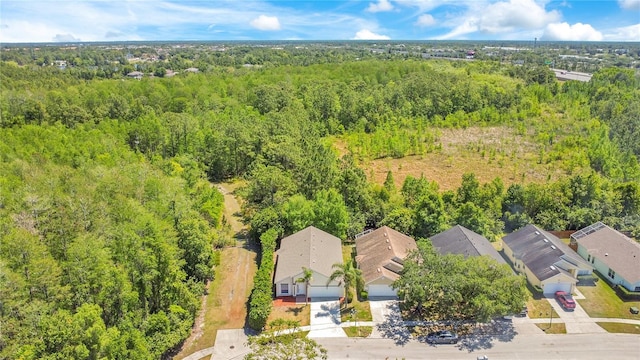 drone / aerial view featuring a wooded view and a residential view