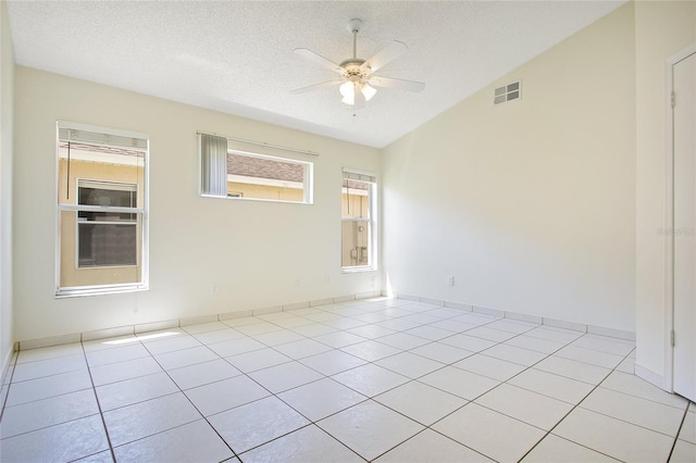 spare room with ceiling fan, lofted ceiling, visible vents, and light tile patterned floors