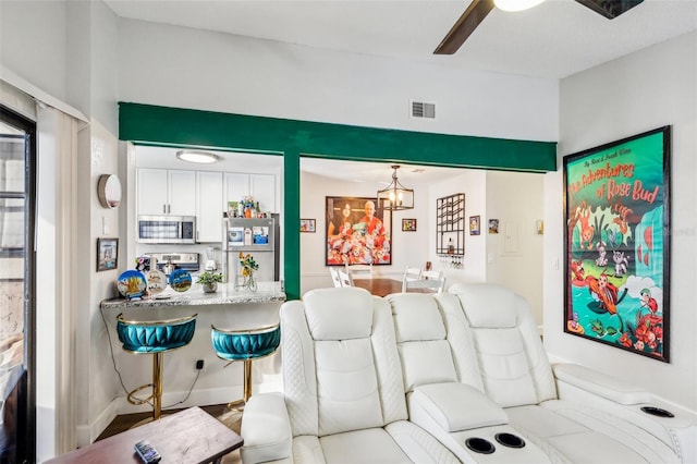 living room with ceiling fan with notable chandelier