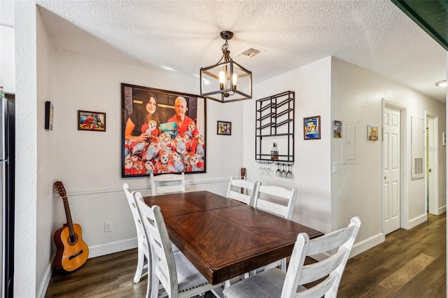 dining space with dark hardwood / wood-style floors, a textured ceiling, and a notable chandelier