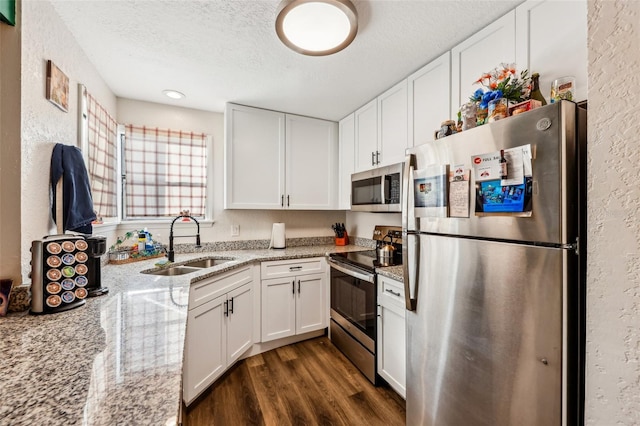 kitchen with light stone counters, sink, stainless steel appliances, and white cabinets