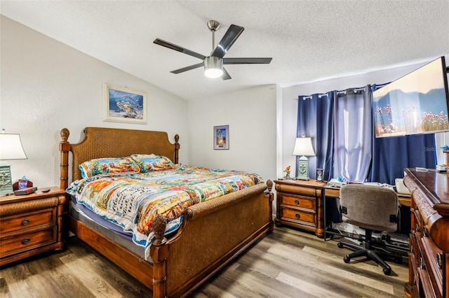 bedroom with wood-type flooring, vaulted ceiling, ceiling fan, and a textured ceiling