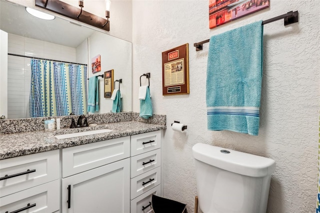 bathroom featuring toilet, vanity, and a shower with shower curtain