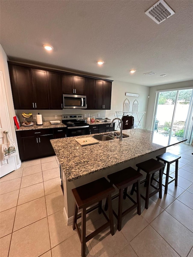 kitchen featuring appliances with stainless steel finishes, an island with sink, a sink, and visible vents