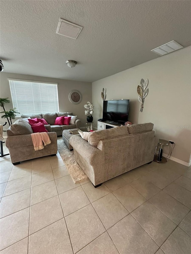 living room featuring light tile patterned floors, a textured ceiling, and visible vents