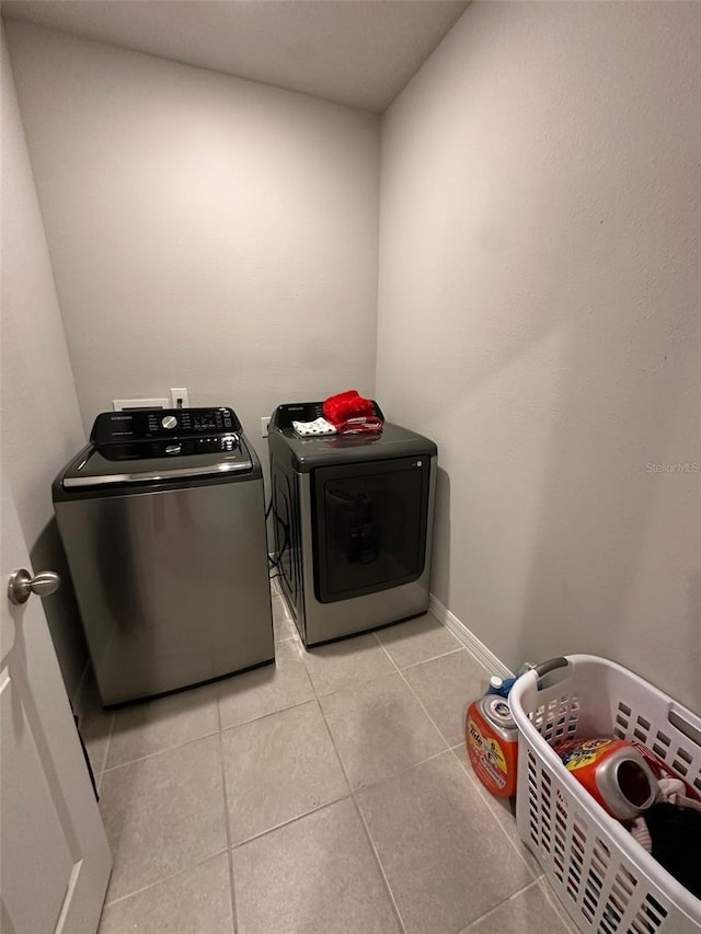 laundry area with laundry area, baseboards, washing machine and clothes dryer, and light tile patterned floors