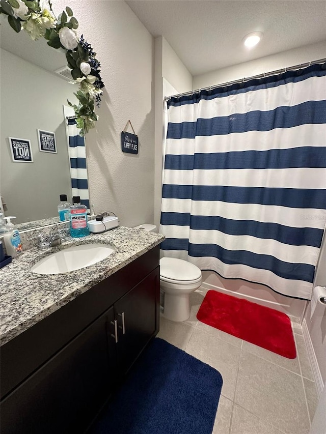 full bathroom featuring toilet, vanity, a textured ceiling, and tile patterned floors