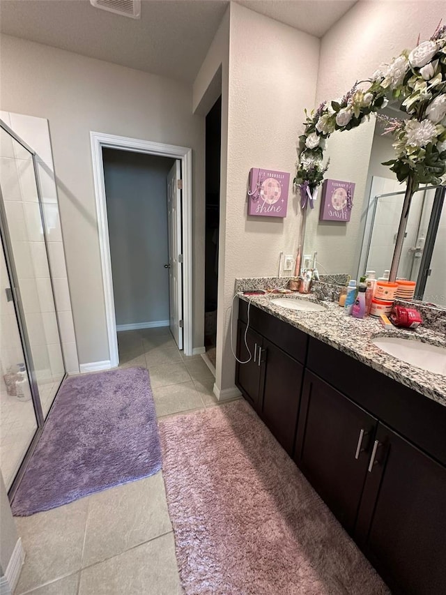 full bath with a stall shower, a sink, and tile patterned floors