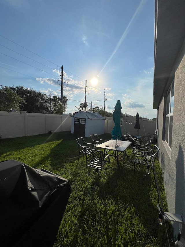 view of yard with an outbuilding, a fenced backyard, and a shed