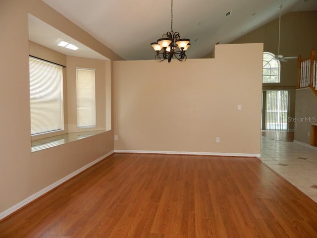 spare room with ceiling fan with notable chandelier, wood-type flooring, and high vaulted ceiling