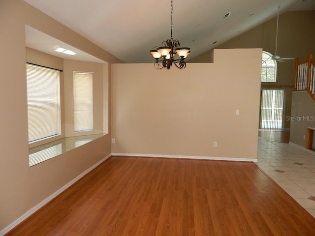 spare room featuring hardwood / wood-style flooring, ceiling fan with notable chandelier, and high vaulted ceiling