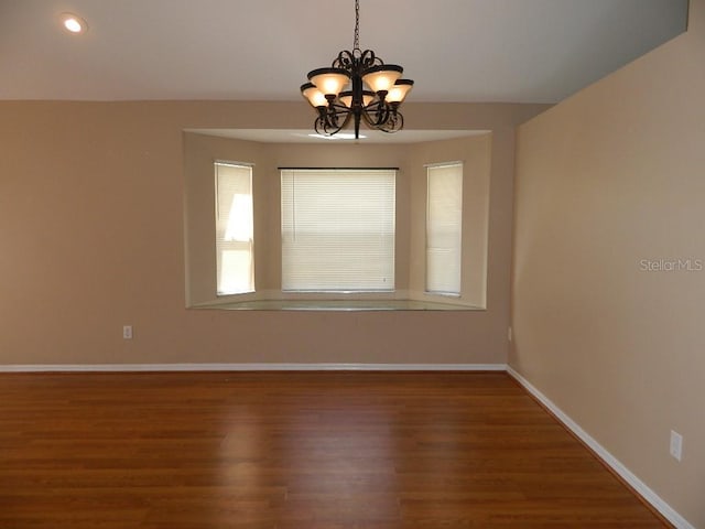 empty room featuring hardwood / wood-style floors and a notable chandelier