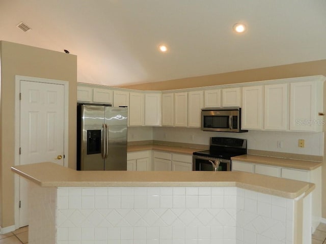 kitchen featuring stainless steel appliances, white cabinetry, lofted ceiling, and light tile patterned floors