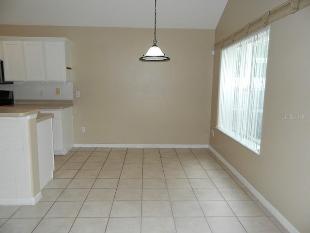 kitchen with pendant lighting, white cabinetry, vaulted ceiling, and light tile patterned floors