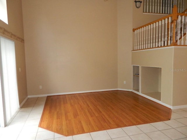 unfurnished living room featuring a towering ceiling and light wood-type flooring