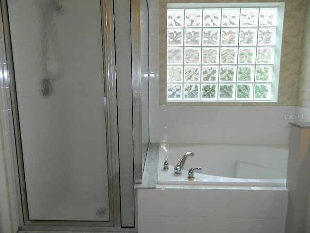 bathroom featuring shower with separate bathtub