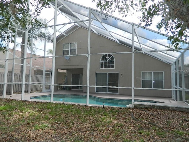 rear view of property featuring a lanai, a fenced in pool, and a patio area