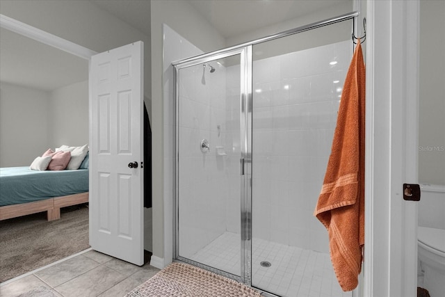 bathroom featuring tile patterned floors, toilet, and a shower with shower door